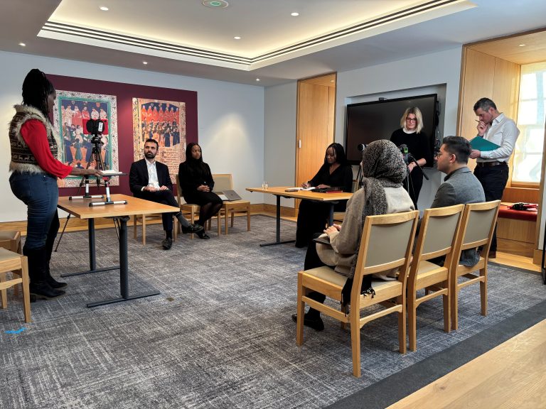 A pupil is filmed doing advocacy training in a meeting room at the Inn, watched by trainers