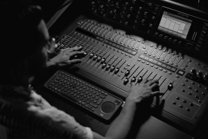 black and white overhead shot of hands at an audio mixing desk