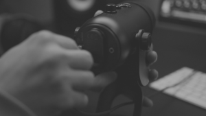 black and white closeup of a hand adjusting a high end studio microphone